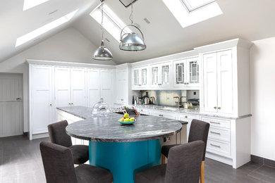Photo of a medium sized traditional l-shaped kitchen in Other with recessed-panel cabinets, white cabinets, marble worktops, mirror splashback, an island, grey floors, a submerged sink, grey splashback, integrated appliances and grey worktops.