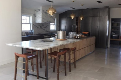 Medium sized contemporary l-shaped kitchen/diner in Boston with marble worktops, stone slab splashback, an island, flat-panel cabinets, dark wood cabinets, stainless steel appliances, a submerged sink, white splashback, porcelain flooring and grey floors.