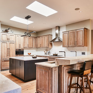 Inspiration for a transitional u-shaped medium tone wood floor and brown floor kitchen remodel in St Louis with an undermount sink, recessed-panel cabinets, medium tone wood cabinets, white backsplash, mosaic tile backsplash, paneled appliances, an island and white countertops