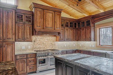 Diseño de cocina clásica grande con fregadero sobremueble, armarios con paneles con relieve, puertas de armario de madera oscura, encimera de granito, salpicadero beige, salpicadero de azulejos de piedra, electrodomésticos de acero inoxidable, suelo de baldosas de cerámica y una isla