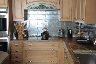 Bild på ett mellanstort, avskilt eklektiskt u-kök, med en rustik diskho, luckor med upphöjd panel, skåp i ljust trä, bänkskiva i kvartsit, stänkskydd med metallisk yta, stänkskydd i tunnelbanekakel, integrerade vitvaror, marmorgolv och en köksö