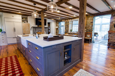 Inspiration for a large farmhouse l-shaped medium tone wood floor and brown floor eat-in kitchen remodel in Other with a farmhouse sink, recessed-panel cabinets, stone slab backsplash, stainless steel appliances, an island, white countertops, white cabinets, marble countertops and white backsplash