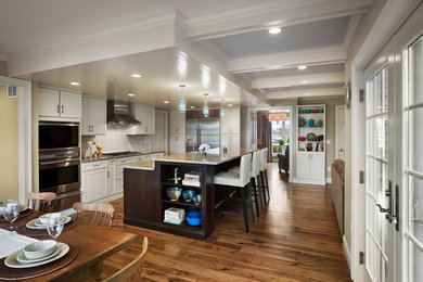 Eat-in kitchen - mid-sized transitional l-shaped medium tone wood floor eat-in kitchen idea in Philadelphia with a farmhouse sink, recessed-panel cabinets, yellow cabinets, quartz countertops, white backsplash, porcelain backsplash and stainless steel appliances