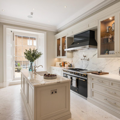 Mid-sized elegant galley marble floor and white floor kitchen photo in London with marble countertops, white backsplash, marble backsplash, an island, white countertops, a farmhouse sink, recessed-panel cabinets, white cabinets and black appliances