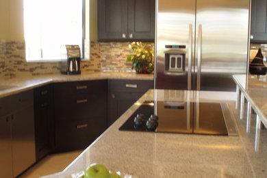 マイアミにある高級な広いコンテンポラリースタイルのおしゃれなキッチン (シェーカースタイル扉のキャビネット、濃色木目調キャビネット、御影石カウンター、石タイルのキッチンパネル、シルバーの調理設備) の写真