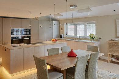 This is an example of a large contemporary l-shaped open plan kitchen in Hampshire with flat-panel cabinets, limestone worktops, beige splashback and an island.