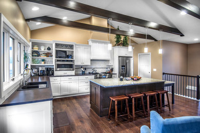 Small arts and crafts l-shaped dark wood floor kitchen photo in Omaha with an undermount sink, recessed-panel cabinets, dark wood cabinets, granite countertops, white backsplash, ceramic backsplash, stainless steel appliances and an island