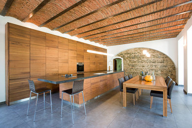 Diseño de cocina lineal rústica con armarios con paneles lisos, puertas de armario marrones, electrodomésticos negros y una isla