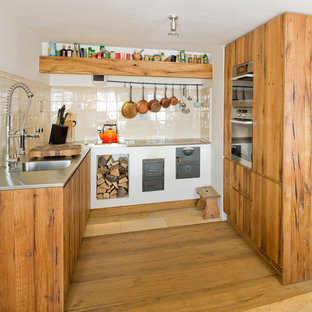 Ispirazione per una cucina ad U stile rurale con lavello integrato, ante lisce, ante con finitura invecchiata, top in acciaio inossidabile e paraspruzzi beige