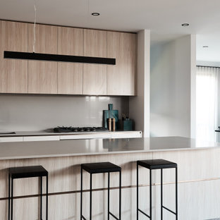 Inspiration for a mid-sized contemporary single-wall eat-in kitchen in Melbourne with an undermount sink, flat-panel cabinets, light wood cabinets, solid surface benchtops, beige splashback, glass sheet splashback, terrazzo floors, with island, grey floor and beige benchtop.