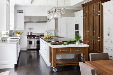 Inspiration for a large timeless u-shaped dark wood floor eat-in kitchen remodel in Boston with a farmhouse sink, shaker cabinets, white cabinets, marble countertops, white backsplash, subway tile backsplash and stainless steel appliances