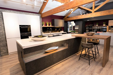 Immagine di una cucina design con paraspruzzi a effetto metallico, paraspruzzi a specchio, elettrodomestici neri e top bianco