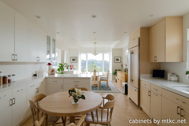 Inspiration for a mid-sized modern l-shaped light wood floor and yellow floor eat-in kitchen remodel in San Francisco with an undermount sink, flat-panel cabinets, light wood cabinets, quartz countertops, white backsplash, quartz backsplash, paneled appliances, a peninsula and white countertops