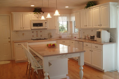 Inspiration for a large timeless u-shaped light wood floor eat-in kitchen remodel in Boston with a double-bowl sink, raised-panel cabinets, white cabinets, soapstone countertops, beige backsplash, subway tile backsplash, stainless steel appliances and an island