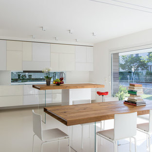 Mittelgroße Moderne Wohnküche mit flächenbündigen Schrankfronten, weißen Schränken, Arbeitsplatte aus Holz, Rückwand aus Spiegelfliesen, weißem Boden, Unterbauwaschbecken und Kücheninsel in Sonstige