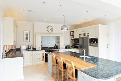 Inspiration for a large traditional grey and cream u-shaped kitchen in West Midlands with recessed-panel cabinets, beige cabinets, an island, beige floors and grey worktops.