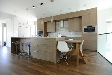 Einzeilige Moderne Wohnküche mit flächenbündigen Schrankfronten, hellen Holzschränken, Mineralwerkstoff-Arbeitsplatte, Küchenrückwand in Weiß, Rückwand aus Steinfliesen, dunklem Holzboden und Kücheninsel in Calgary