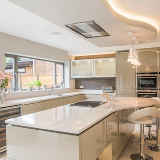 This is an example of a contemporary kitchen in West Midlands with flat-panel cabinets, beige cabinets, brown splashback, an island, white floors and white worktops.