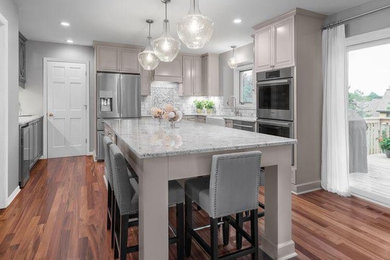 Open concept kitchen - large u-shaped medium tone wood floor and brown floor open concept kitchen idea in Atlanta with a farmhouse sink, shaker cabinets, white cabinets, marble countertops, multicolored backsplash, ceramic backsplash, stainless steel appliances and an island