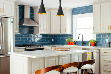 Inspiration for a mid-sized transitional l-shaped medium tone wood floor kitchen remodel in New York with raised-panel cabinets, white cabinets, blue backsplash, subway tile backsplash, stainless steel appliances, an island and white countertops
