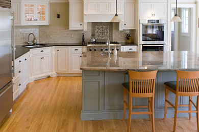 Example of a large classic l-shaped light wood floor eat-in kitchen design in Seattle with an undermount sink, shaker cabinets, white cabinets, granite countertops, beige backsplash, subway tile backsplash, stainless steel appliances and an island