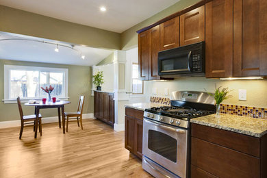 Example of a mid-sized classic single-wall light wood floor eat-in kitchen design in Seattle with shaker cabinets, dark wood cabinets, granite countertops, multicolored backsplash, mosaic tile backsplash, stainless steel appliances and no island