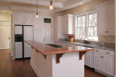 Inspiration for a mid-sized timeless l-shaped dark wood floor eat-in kitchen remodel in Seattle with an undermount sink, raised-panel cabinets, white cabinets, wood countertops, paneled appliances and an island