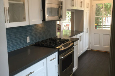 Example of a small transitional galley slate floor and gray floor enclosed kitchen design in Los Angeles with an undermount sink, shaker cabinets, white cabinets, solid surface countertops, blue backsplash, matchstick tile backsplash, stainless steel appliances, no island and gray countertops