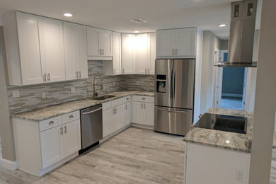 Mid-sized transitional l-shaped light wood floor and gray floor enclosed kitchen photo in Other with an undermount sink, shaker cabinets, white cabinets, granite countertops, multicolored backsplash, matchstick tile backsplash, stainless steel appliances, no island and gray countertops