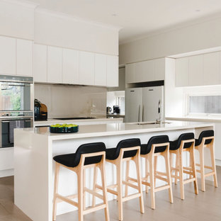 Contemporary kitchen in Melbourne with an undermount sink, flat-panel cabinets, white cabinets, beige splashback, stone slab splashback, with island, beige floor and beige benchtop.