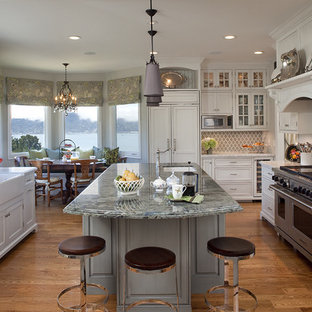 Foto di una cucina chic con lavello stile country, ante in stile shaker, top in granito, paraspruzzi con piastrelle in ceramica, pavimento in legno massello medio, isola, elettrodomestici da incasso e ante bianche