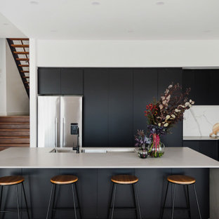 Inspiration for a contemporary l-shaped kitchen in Melbourne with a triple-bowl sink, flat-panel cabinets, black cabinets, multi-coloured splashback, stone slab splashback, stainless steel appliances, dark hardwood floors, with island, brown floor and grey benchtop.