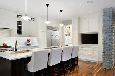Inspiration for a medium sized classic l-shaped kitchen/diner in Toronto with a submerged sink, shaker cabinets, white cabinets, engineered stone countertops, white splashback, porcelain splashback, stainless steel appliances, medium hardwood flooring and an island.