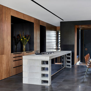Mid-sized contemporary galley open plan kitchen in Melbourne with an undermount sink, recessed-panel cabinets, brown cabinets, concrete benchtops, white splashback, mirror splashback, panelled appliances, with island, grey floor, grey benchtop and recessed.