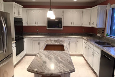This is an example of a medium sized classic u-shaped kitchen pantry in Other with a double-bowl sink, raised-panel cabinets, white cabinets, granite worktops, black appliances, ceramic flooring, an island and beige floors.