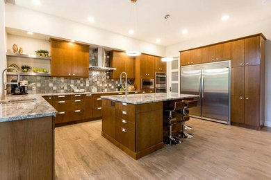 Inspiration for a contemporary l-shaped light wood floor eat-in kitchen remodel in Calgary with a double-bowl sink, flat-panel cabinets, light wood cabinets, granite countertops, multicolored backsplash, ceramic backsplash, stainless steel appliances and an island