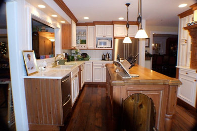 Modelo de cocinas en L clásica cerrada con armarios con paneles con relieve, puertas de armario blancas, encimera de madera y una isla