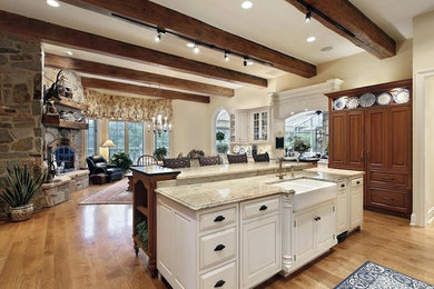 Inspiration for a medium sized traditional l-shaped kitchen in Boston with a belfast sink, recessed-panel cabinets, white cabinets, marble worktops, stainless steel appliances, medium hardwood flooring and an island.