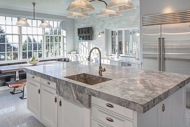 Example of a mid-sized classic single-wall concrete floor and gray floor eat-in kitchen design in Houston with a farmhouse sink, recessed-panel cabinets, white cabinets, granite countertops, gray backsplash, marble backsplash, stainless steel appliances, an island and gray countertops