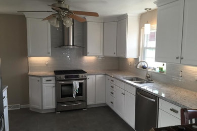 Mid-sized elegant u-shaped eat-in kitchen photo in Other with a double-bowl sink, recessed-panel cabinets, white cabinets, granite countertops, gray backsplash, glass tile backsplash and stainless steel appliances