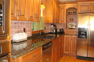Example of a mid-sized single-wall medium tone wood floor kitchen design in Boston with a double-bowl sink, raised-panel cabinets, medium tone wood cabinets, granite countertops, red backsplash, ceramic backsplash and stainless steel appliances