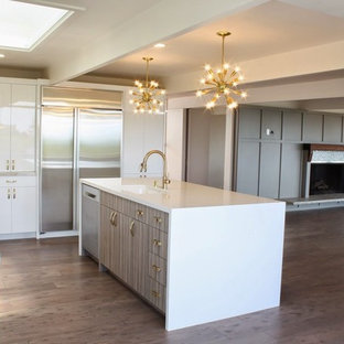Cette image montre une grand cuisine minimaliste en L avec un évier encastré, un placard à porte plane, des portes de placard blanches, un plan de travail en quartz, une crédence beige, une crédence en carreau de porcelaine, un électroménager en acier inoxydable, un sol en vinyl, un îlot central et un sol marron.