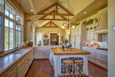 Inspiration for a large cottage u-shaped medium tone wood floor eat-in kitchen remodel in Salt Lake City with an island, a double-bowl sink, raised-panel cabinets, white cabinets, granite countertops, white backsplash, ceramic backsplash and paneled appliances