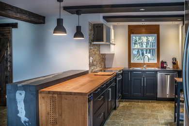 Bild på ett mellanstort funkis kök, med en nedsänkt diskho, skåp i shakerstil, svarta skåp, träbänkskiva, beige stänkskydd, stänkskydd i stenkakel, rostfria vitvaror, klinkergolv i keramik och en köksö