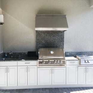 Ejemplo de cocina comedor lineal, minimalista, de tamaño medio, con fregadero de un seno, encimera de granito, salpicadero multicolor, puertas de granito, electrodomésticos de acero inoxidable, suelo de ladrillo, suelo marrón y encimeras marrones