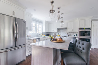 Kitchen photo in New York with white cabinets, stainless steel appliances and an island