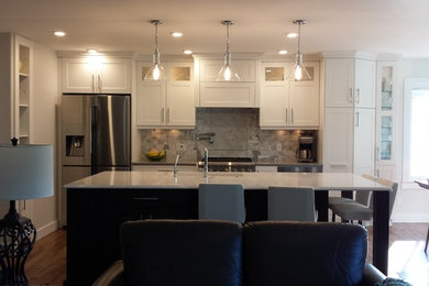 Example of a transitional medium tone wood floor kitchen design in Other with an undermount sink, flat-panel cabinets, white cabinets, quartz countertops, gray backsplash, stone tile backsplash, stainless steel appliances and an island