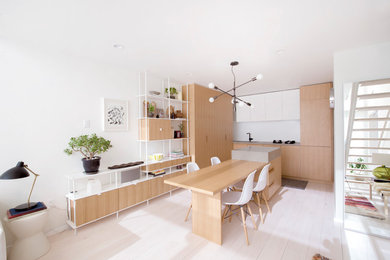 Foto di una cucina minimal con ante lisce, ante in legno chiaro, parquet chiaro, pavimento bianco, lavello sottopiano, top in cemento, elettrodomestici da incasso e top grigio