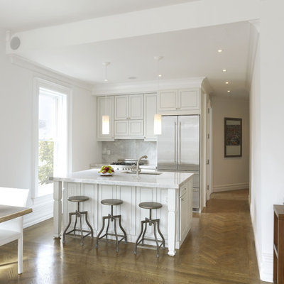 Example of a small trendy galley medium tone wood floor and brown floor eat-in kitchen design in New York with stainless steel appliances, an undermount sink, recessed-panel cabinets, white cabinets, quartzite countertops, stone slab backsplash, an island and gray backsplash