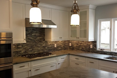 Example of a mid-sized tuscan u-shaped dark wood floor open concept kitchen design in Los Angeles with an undermount sink, shaker cabinets, white cabinets, quartzite countertops, gray backsplash, glass tile backsplash, stainless steel appliances and an island